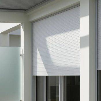 Persianas em PVC da Controsol instaladas na janela, com acabamento branco e controlo de luz.