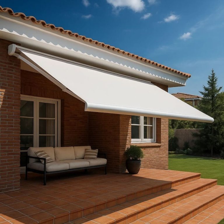 Toldo de braços articulados instalado numa moradia, a sombrear o terraço exterior com estrutura branca e lona clara.