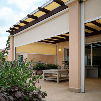 Toldo vertical guiado por calha instalado numa pérgola, para proteção solar e maior estabilidade ao vento.